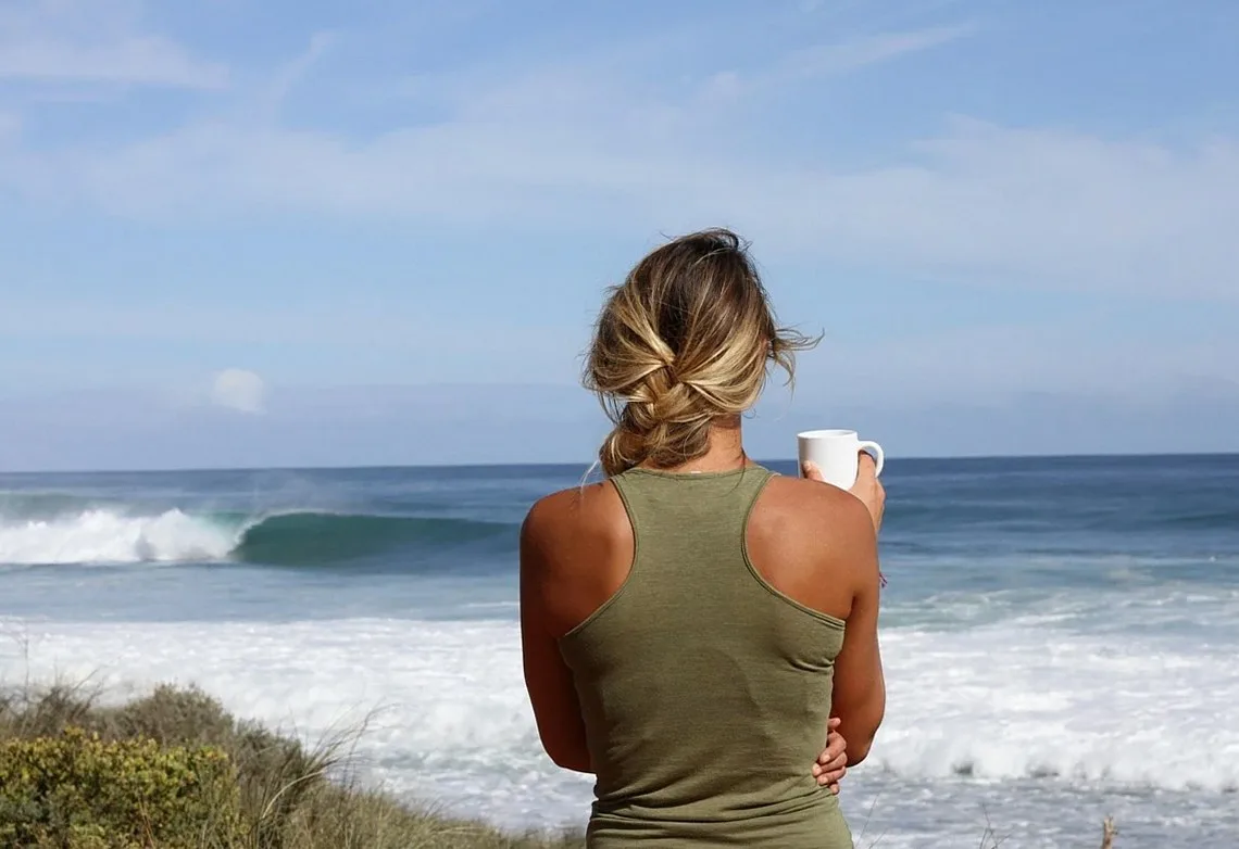 Person holding a cup and looking at breaking waves