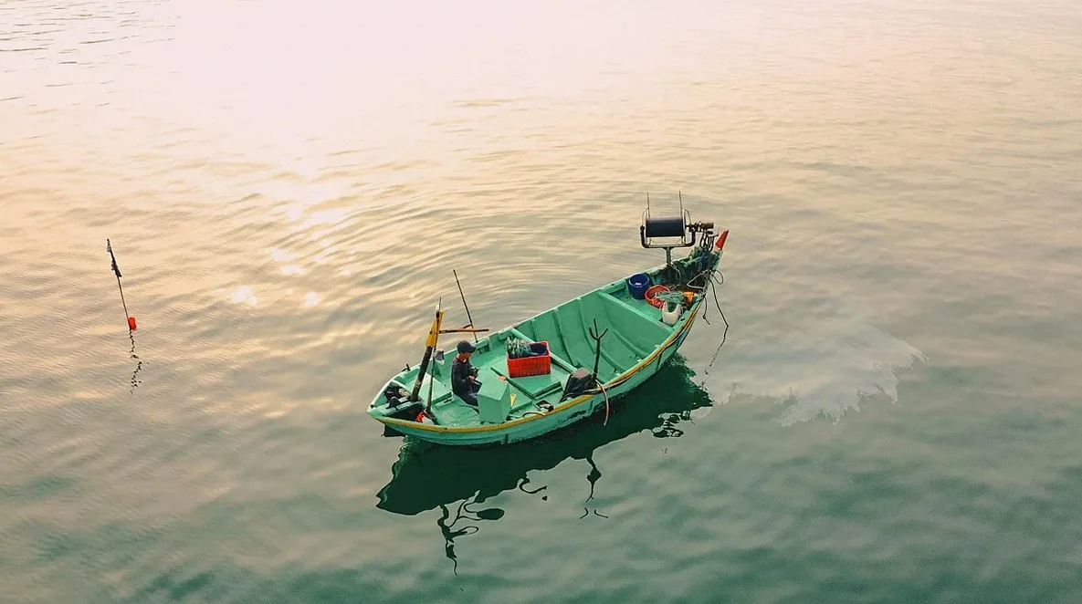 Small green fishing boat on calm water