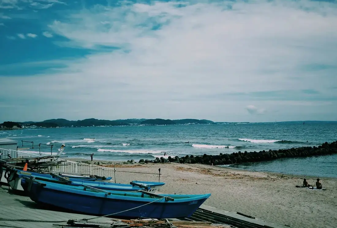 Blue boats pulled up on a beach under a cloudy sky